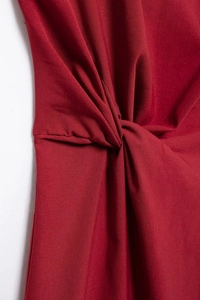 Gros plan sur le détail du nœud torsadé de cette robe mi-longue en tricot rouge foncé