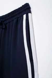 Detail of dark blue track pants with elastic drawstring waist and side white stripes