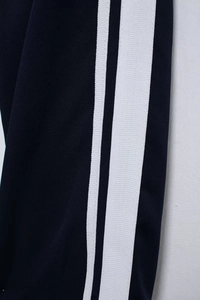 Macro detail of navy blue knit tracksuit with classic double white side stripe accents