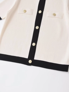 Detail of knit cardigan with black contrast trim and gold lion relief buttons