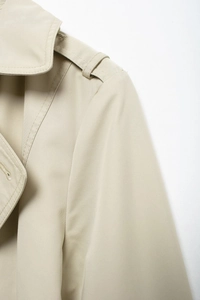 Detailed close-up of high-density twill fabric on khaki trench coat shoulder straps