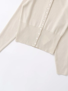 Detailed view of cream knit cardigan with fine ribbing and matching round buttons