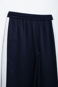 Detail of navy blue track pants with white side stripes and elastic drawstring waist