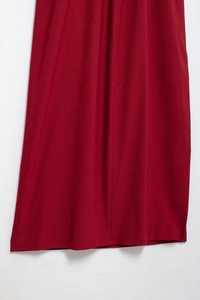 Vue détaillée du tissu rouge foncé d'une robe midi avec coutures verticales et texture lisse