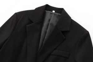 Detail shot of black suit jacket featuring peak lapel and premium twill fabric texture