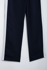 Detail view of navy blue track pants featuring classic white side stripes and straight cut