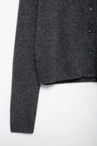 Close-up of dark grey wool knit cardigan featuring round buttons and ribbed cuffs