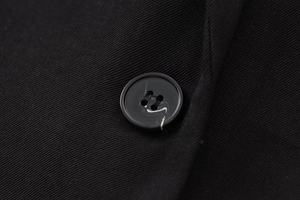 Macro shot of a black twill blazer featuring a marbled resin button and fabric texture