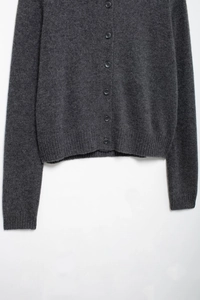 Close-up of dark grey knit cardigan showing rib-knit hem and high-quality wool texture