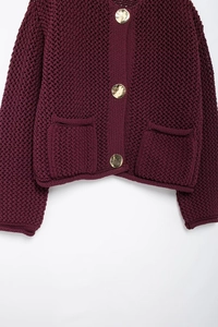 Close-up of chunky knit wine red cardigan with gold buttons and functional pockets