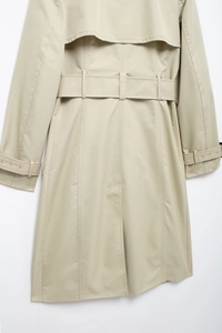 Detail view of the back rain shield and belted waist of this slim beige trench coat