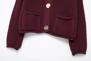 Detailed close-up of wine red chunky knit cardigan featuring gold buttons and pockets