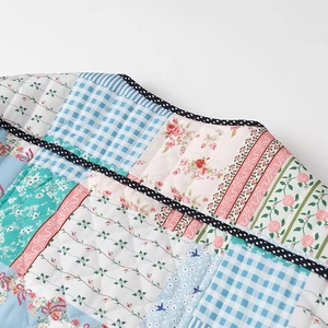 Detailed macro view of quilted patchwork fabric with floral patterns and polka dot edges