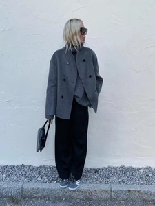 Detail of grey double-breasted wool coat with wide silhouette and textured fabric