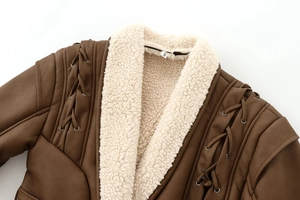 Detail der braunen Wildlederjacke mit dickem Plüschkragen und Schnürdesign an den Ärmeln