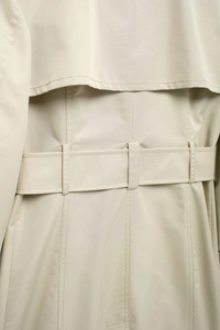 Close-up detail of beige trench coat back storm flap and waist belt with fine stitching