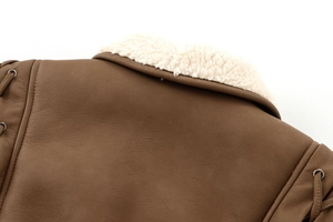 Detail von brauner Wildlederjacke mit weißem Pelzkragen und Schnürung mit Metallösen