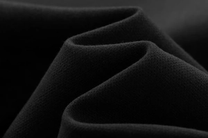Detailed macro view of black knitted fabric texture with soft drapes and elegant folds