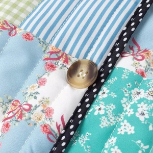 Detail of patchwork quilted jacket with floral patterns, stripes, and a wooden button