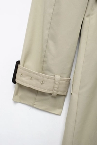 Detail of khaki trench coat sleeve with adjustable buckle strap and twill fabric texture
