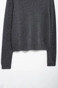 Detailed close-up of dark grey knitwear featuring ribbed hem and fine wool texture