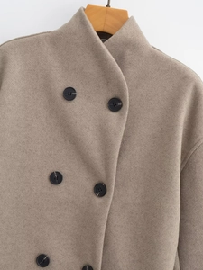 Detail of oatmeal wool coat fabric featuring classic black double-breasted buttons