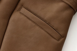 Detail einer dunkelbraunen Wildlederjacke mit feiner Doppelnaht und Paspeltasche