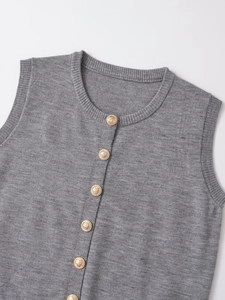 Detail of grey knitted vest showing fine texture and decorative gold embossed buttons