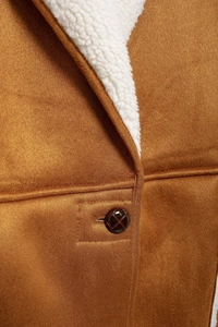 Close-up of brown suede coat featuring white shearling lining and checkered button detail