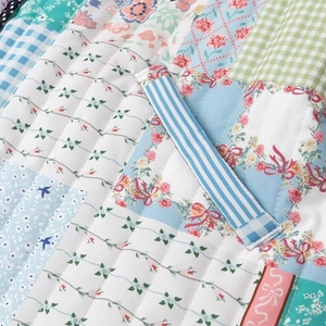 Detailed close-up of patchwork quilting on women's winter jacket with floral patterns