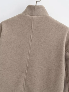 Detail view of the camel wool blend coat featuring back seam stitching and texture