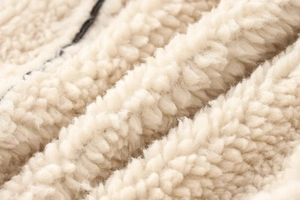 Makroaufnahme der cremeweißen Lammfell-Textur und des weichen Fleecefutters der Jacke