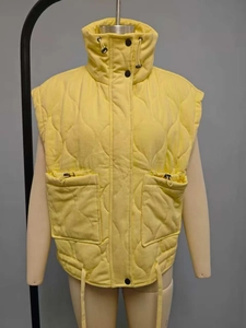 Detail of yellow quilted vest showing diamond pattern, high collar, and cargo pockets