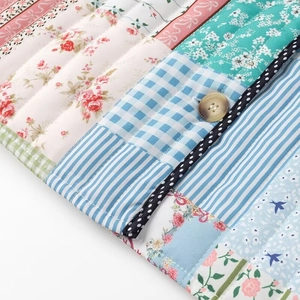 Close-up of quilted patchwork fabric with floral patterns and beige button closure