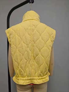 Detail view of lemon yellow quilted vest featuring windproof stand collar and elastic hem