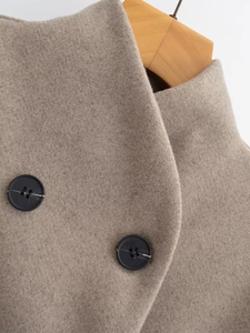 Close-up of oatmeal wool coat collar with classic black buttons on a wooden hanger