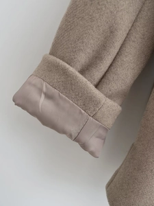 Detail of wool blend coat cuff with smooth satin lining in elegant taupe color