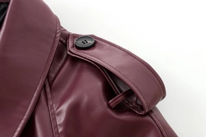 Detail of burgundy leather jacket shoulder featuring decorative epaulette and black button