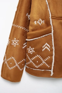 Detail of brown suede jacket with white ethnic embroidery and soft faux shearling lining
