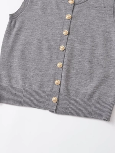 Detail of grey knitted vest with round neck and ornate gold embossed buttons