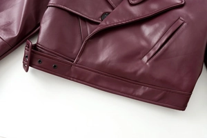 Detail of burgundy PU leather biker jacket showing waist belt buckle and silver eyelets