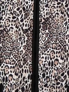 Macro detail of diamond-quilted leopard print fabric with black piping on the edge