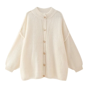 Close-up of cream knit cardigan featuring ornate gold buttons and textured ribbing