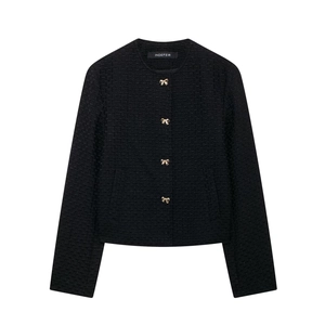 Détail de veste en tweed noir avec des boutons dorés en forme de nœud papillon