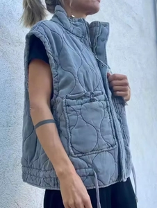 Detail of grey quilted vest featuring a stand collar and drawstring pocket on the side