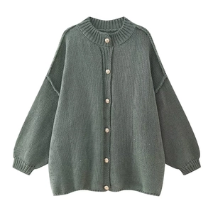 Detail of dark green knit cardigan featuring coarse texture and gold metal buttons