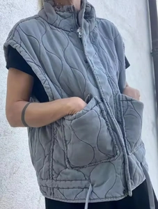 Detail of grey wave-quilted vest featuring stand collar, zipper closure, and large pockets