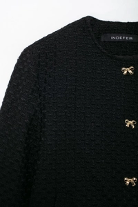 Détail de la veste en tweed noir avec boutons dorés en forme de nœud et col rond élégant