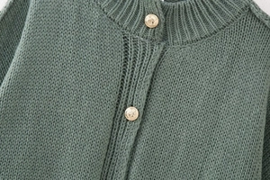 Close-up of sage green chunky knit sweater with vintage embossed golden buttons