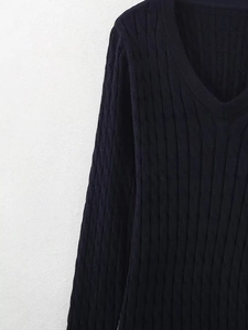 Gros plan sur un pull en maille torsadée bleu marine avec col en V et texture tressée nette